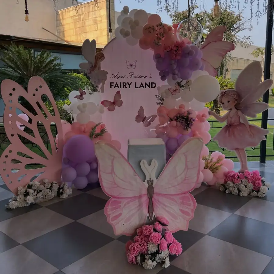 Fairyland birthday stage with a giant butterfly, fairy cut-outs and pastel balloons