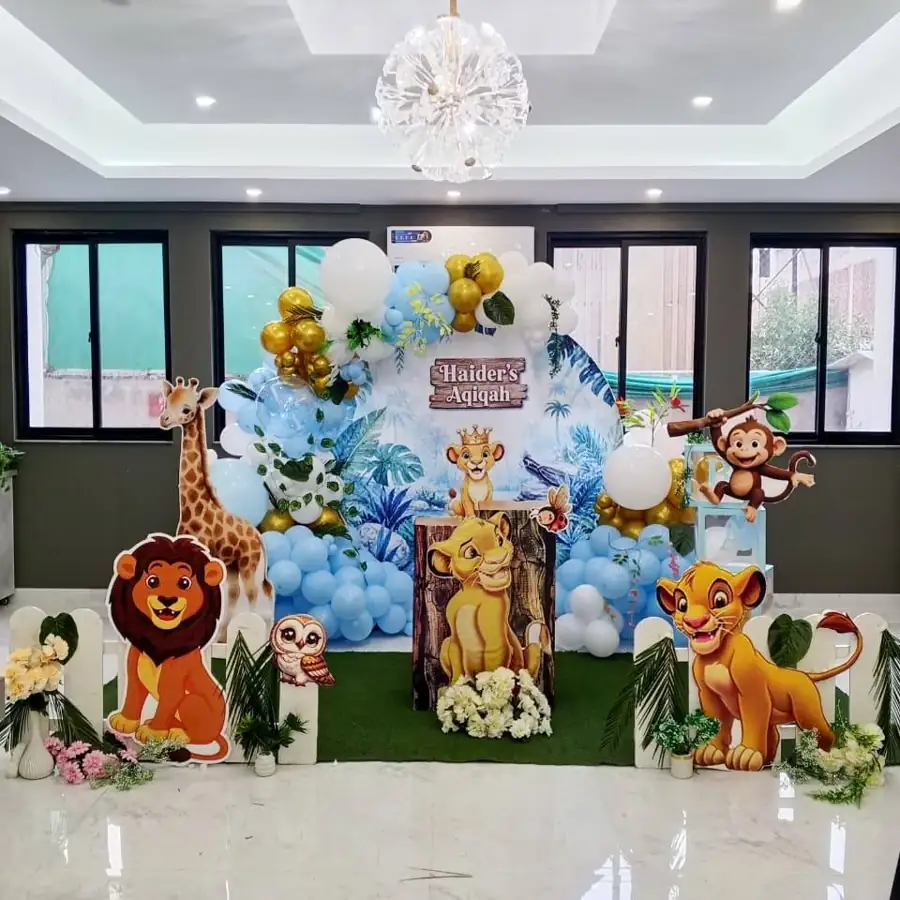 Lion King themed birthday backdrop with cut-out lion characters and a balloon arch