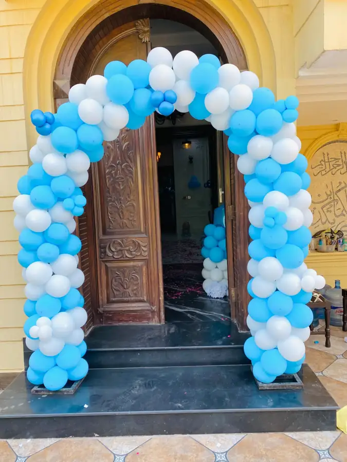 Blue and white balloon arch around the front door of a house