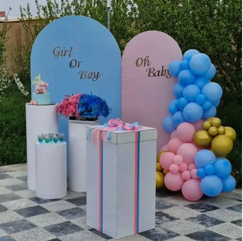 Gender reveal setup with blue and pink arches, gift boxes and balloons