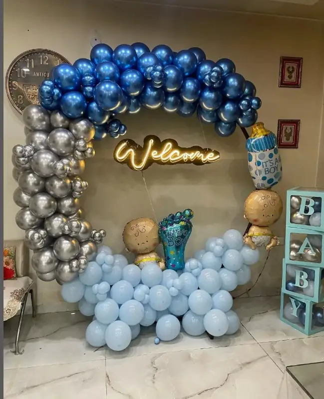 Round welcome baby backdrop with navy and silver balloons and baby footprints
