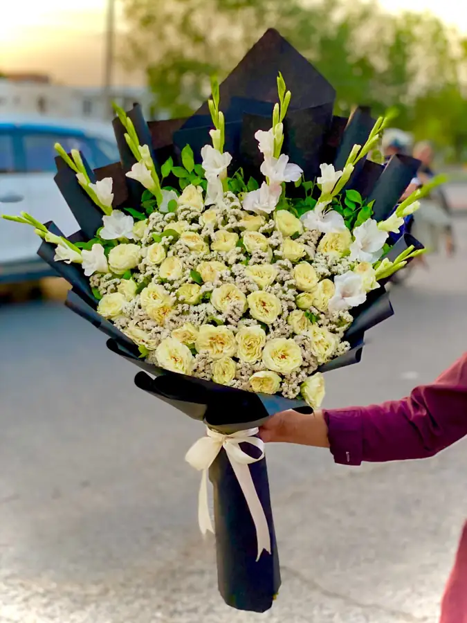 Large bouquet of cream and white roses with gladiolus in black wrapping