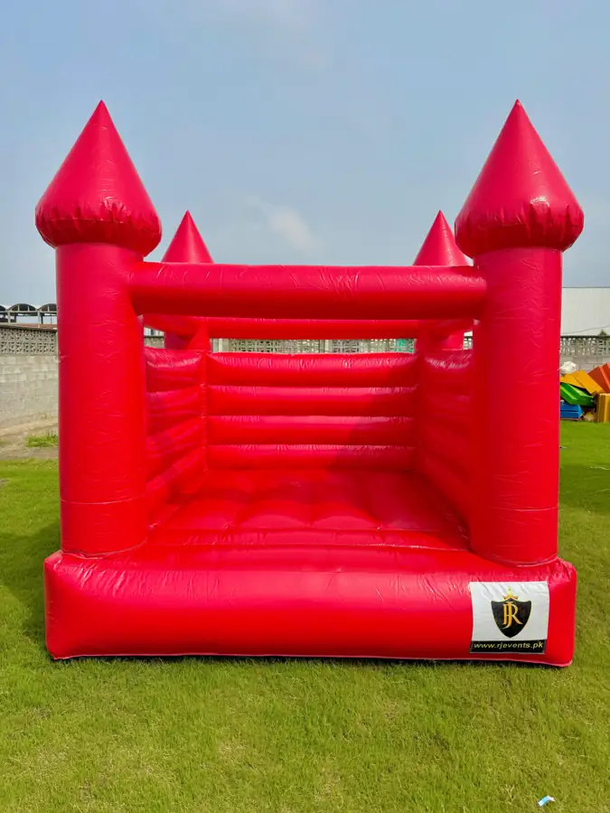 Red bouncy castle with towers on a green lawn