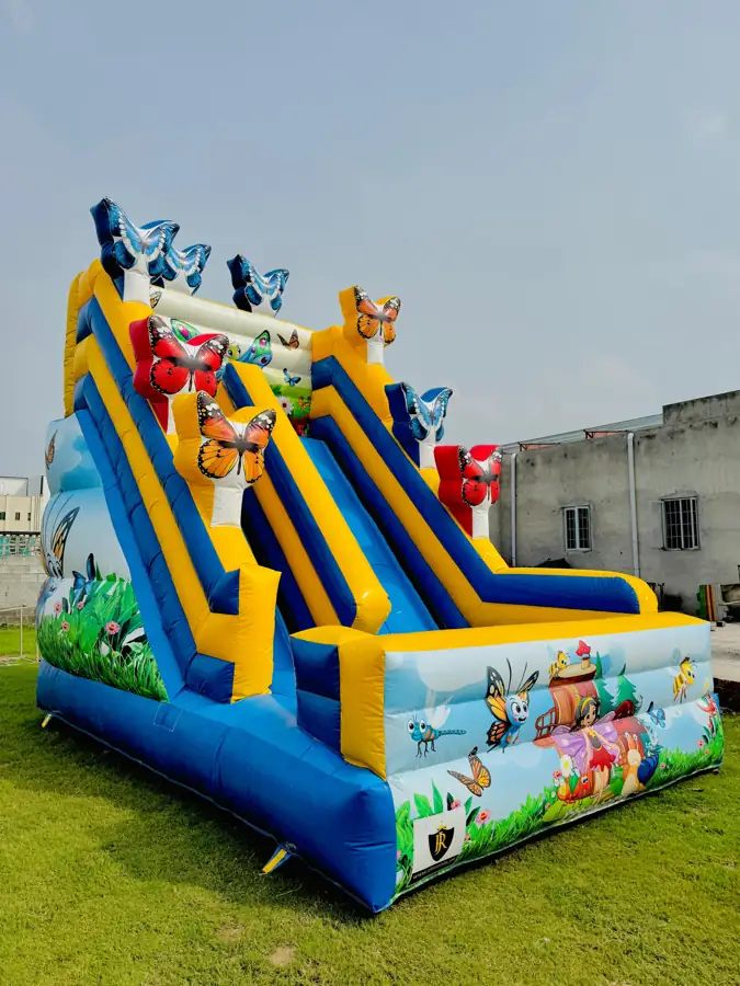 Large inflatable slide with cartoon characters printed on it, set up on a lawn