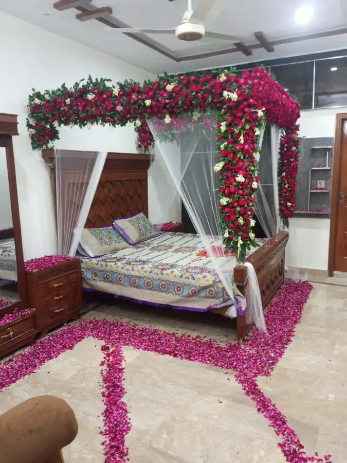 Bedroom with a red rose canopy over the bed and rose petals on the floor