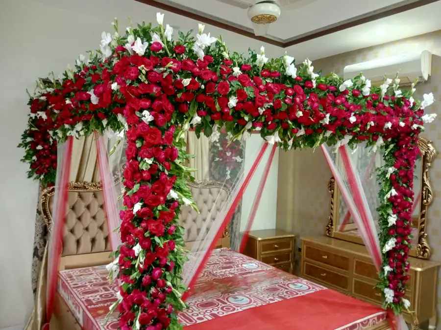 Bedroom with a canopy bed covered in red flowers and white fabric