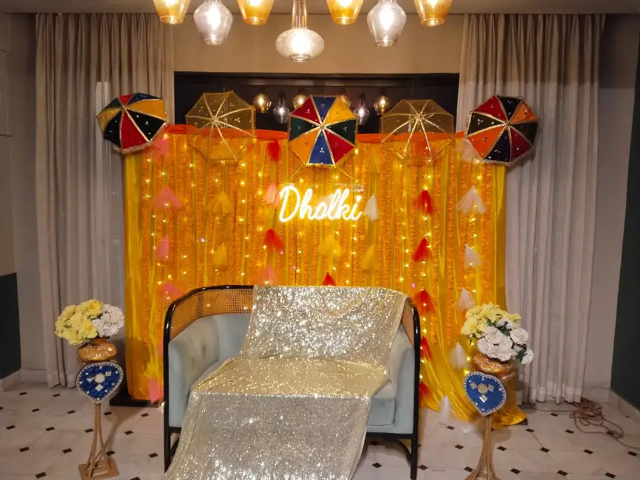 Mayun stage with yellow drapes, umbrellas, a sparkle cushion seat and marigold flowers