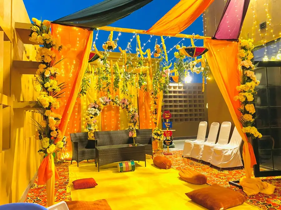 Mayun setup in a hall with orange drapes, hanging flowers and sofa seating
