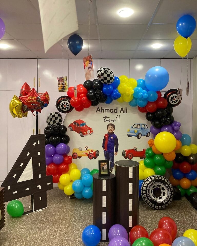 Cars and racing theme fourth birthday setup with colourful balloons and a road display