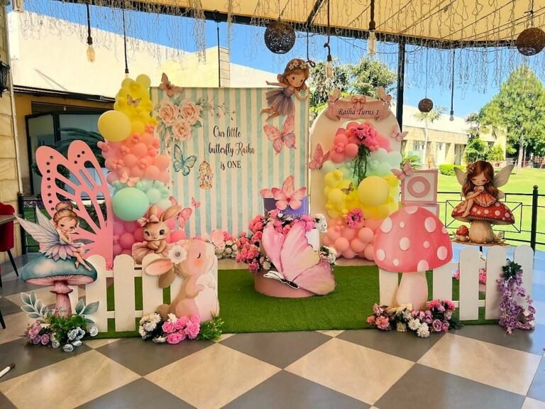 Fairy and butterfly theme birthday backdrop on an outdoor stage with a picket fence