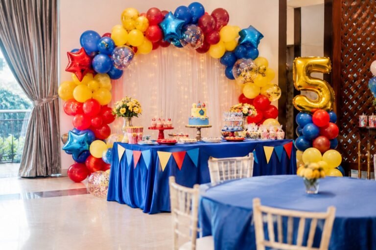 Kids birthday party hall with a red, yellow and blue balloon arch and dessert table