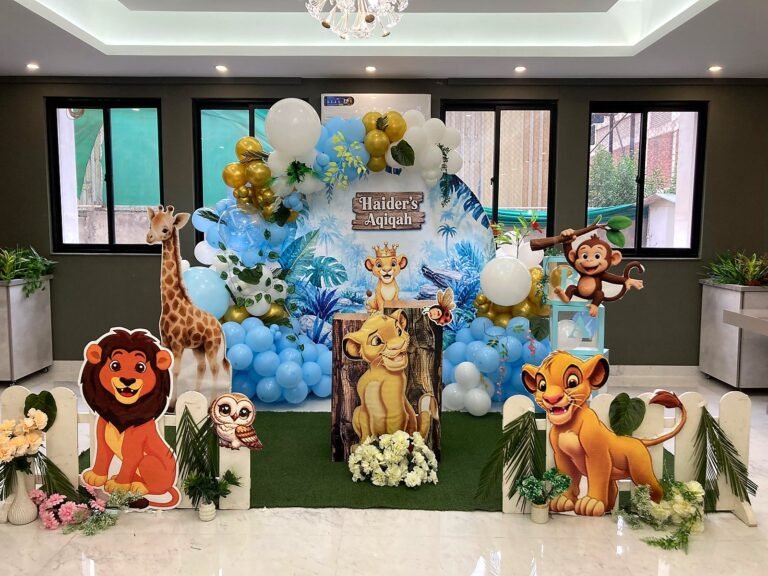 Lion King birthday backdrop with blue balloons, character cut-outs and a green grass floor