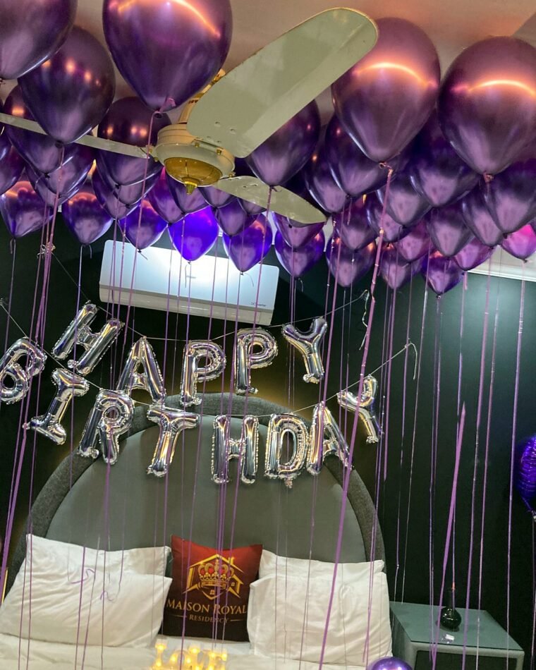 Birthday room with a purple balloon ceiling and silver Happy Birthday letters