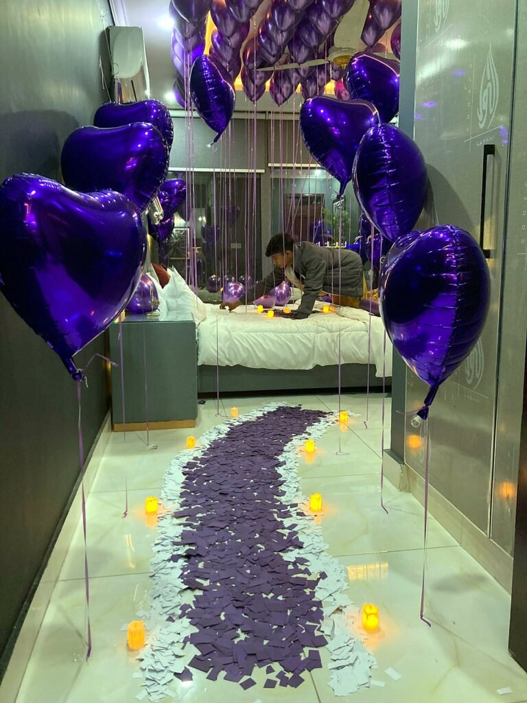 Room with purple heart foil balloons and a purple petal path leading to a bed