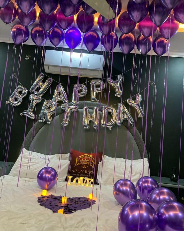Purple and silver balloon birthday room with candles and rose petals