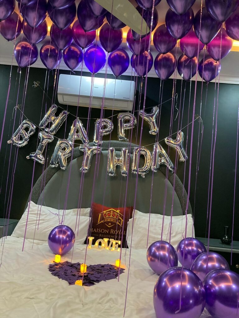 Purple and silver balloon birthday room with candles and rose petals