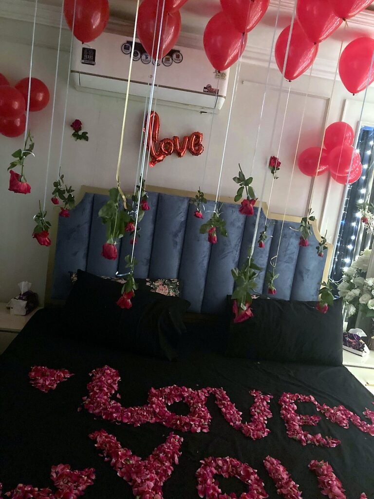 Bedroom with red balloons, a love sign and rose petals spelling love you