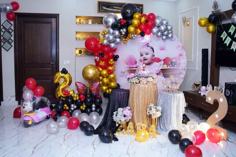 Second birthday setup with red, gold and black balloons and number balloons