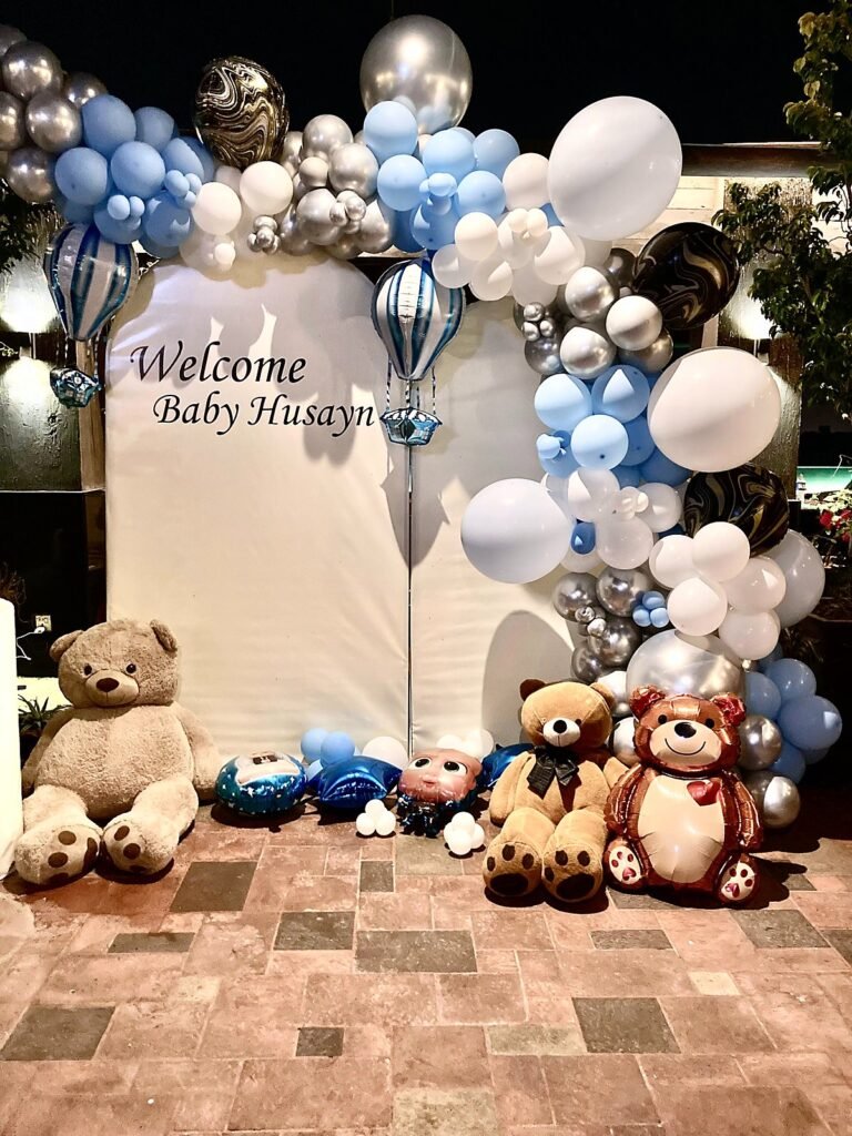 Welcome baby setup with a blue, silver and white balloon arch and teddy bears